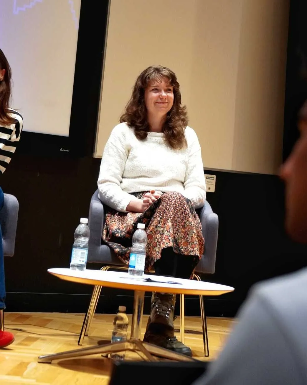 A mid-range shot of Amy on a stage panel, looking up at the crowd.